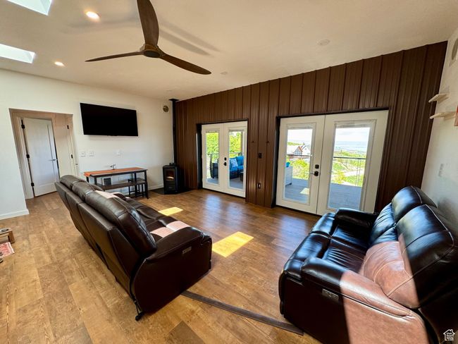 Living area with french doors, plenty of natural light, ceiling fan, light wood-type flooring, metal accent wall, and new leather couch & loveseat | Image 8