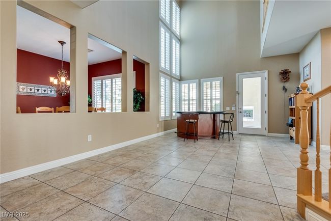 Entryway featuring a chandelier, a bar, light tile patterned floors, baseboards, and a towering ceiling | Image 13