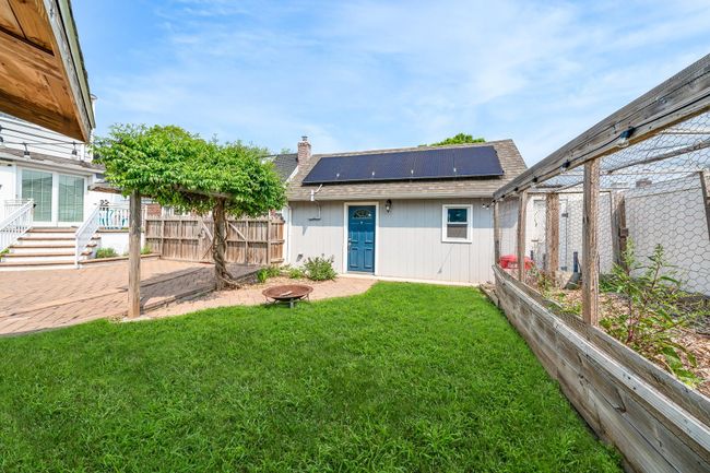 Rear view of property featuring roof mounted solar panels, roof with shingles, and a chimney | Image 7