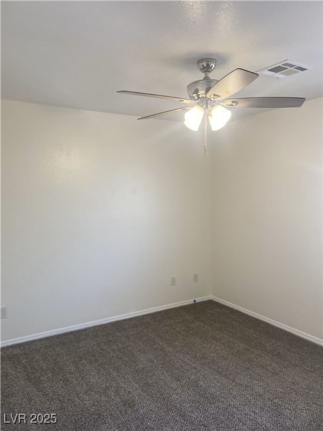 Unfurnished room featuring ceiling fan, baseboards, dark colored carpet, and visible vents | Image 12