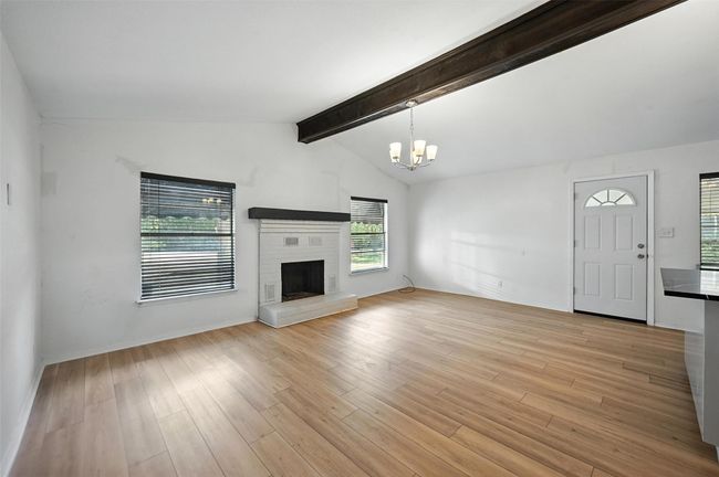 Unfurnished living room with light wood finished floors, a chandelier, and a brick fireplace | Image 6