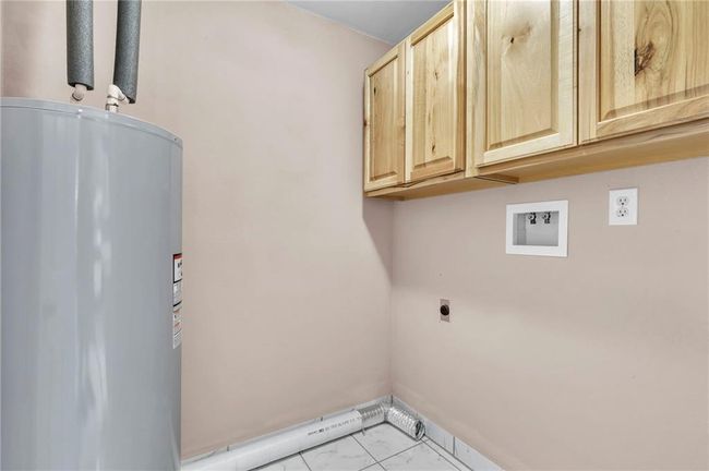 Laundry area with electric water heater, hookup for an electric dryer, marble finish floor, cabinet space, and washer hookup | Image 26