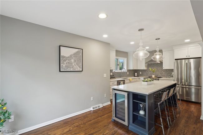 Kitchen with recessed lighting, decorative backsplash, a breakfast bar, stainless steel appliances, and white cabinetry | Image 18