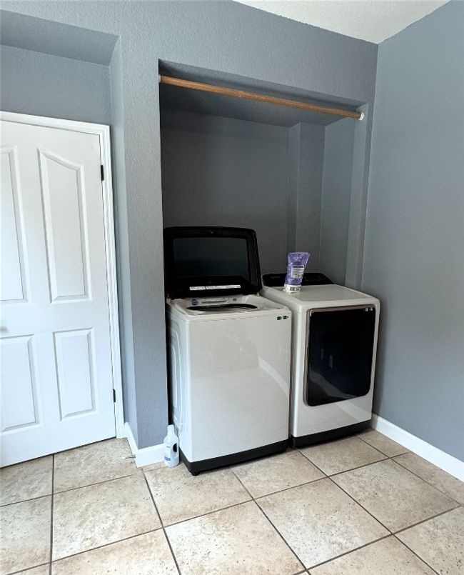Laundry area with washer and dryer and light tile patterned flooring. | Image 15