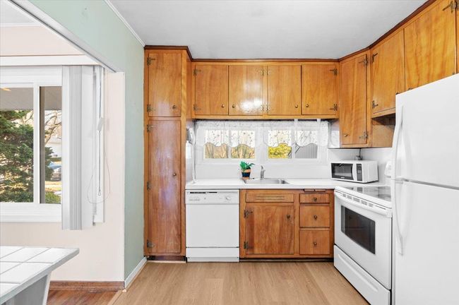 Kitchen featuring sink, crown molding, white appliances, light hardwood / wood-style flooring, and tile countertops | Image 7