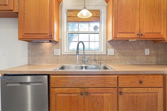 Kitchen with stainless steel dishwasher, a sink, tasteful backsplash, and light countertops | Image 17