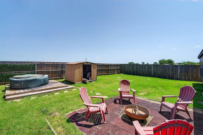 Fenced backyard with an outdoor fire pit, a storage shed, and a patio | Image 33