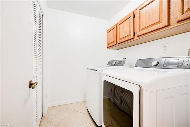 Washroom featuring light tile patterned floors, cabinet space, baseboards, and washer and clothes dryer | Image 25