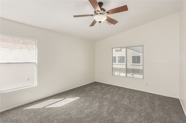 Carpeted primary featuring visible vents, baseboards, vaulted ceiling, and ceiling fan | Image 12