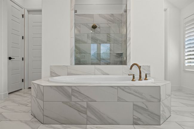 Full bathroom with marble look tile flooring, a garden tub, and tiled shower | Image 25