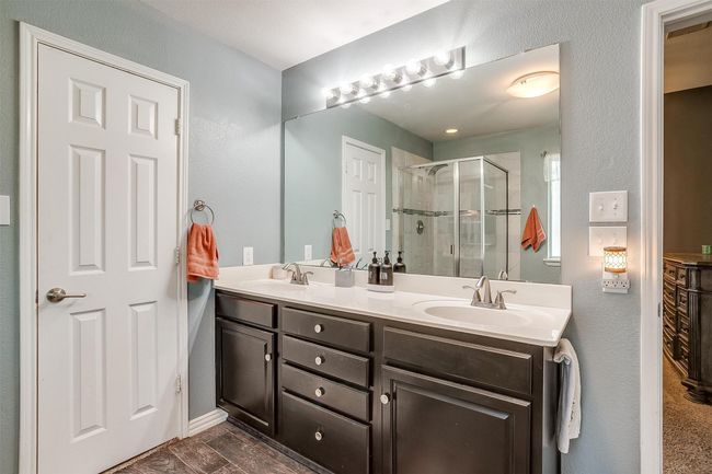 Full bath with a stall shower, double vanity, baseboards, and a textured wall | Image 28