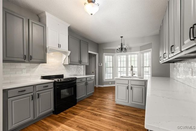 Kitchen featuring black / electric stove, gray cabinetry, a sink, a chandelier, and a textured ceiling | Image 16