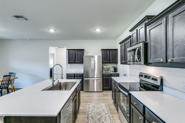 Kitchen featuring light hardwood / wood-style floors, stainless steel appliances, a center island with sink, and sink | Image 11