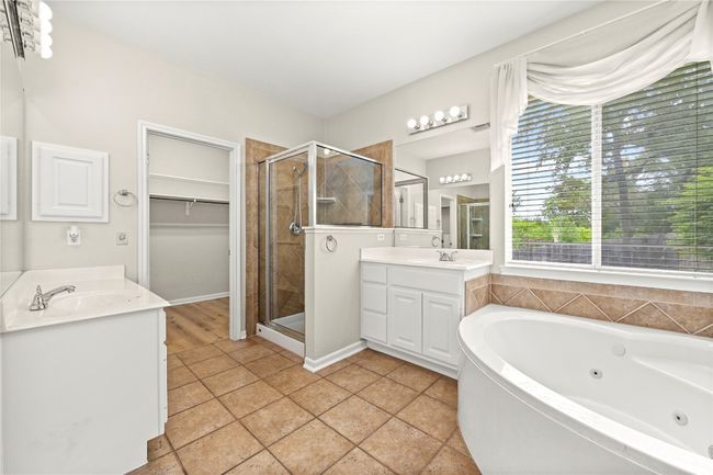 Bathroom featuring a whirlpool tub, a stall shower, vanity, and a spacious closet | Image 15