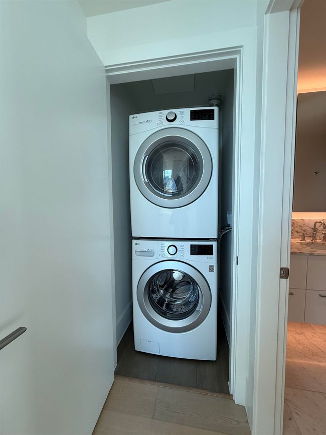 Clothes washing area with laundry area, a sink, stacked washing maching and dryer, and tile patterned flooring | Image 16