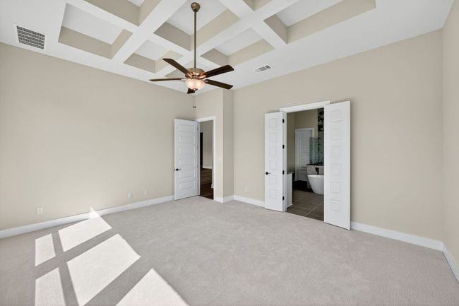 Unfurnished bedroom with coffered ceiling, light carpet, ceiling fan, beam ceiling, and connected bathroom | Image 12