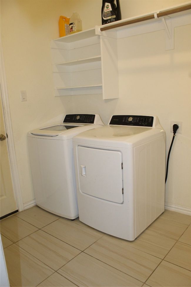Clothes washing area featuring independent washer and dryer, light tile patterned flooring, and baseboards | Image 18
