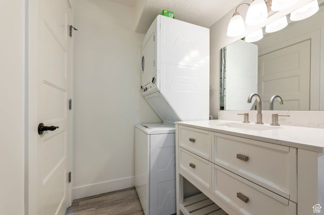 Clothes washing area with stacked washer / drying machine, laundry area, a sink, light wood-style floors, and baseboards | Image 32