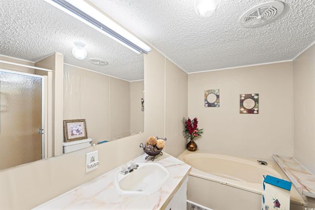 Full bath with a textured ceiling, vanity, a bath, and a stall shower | Image 12