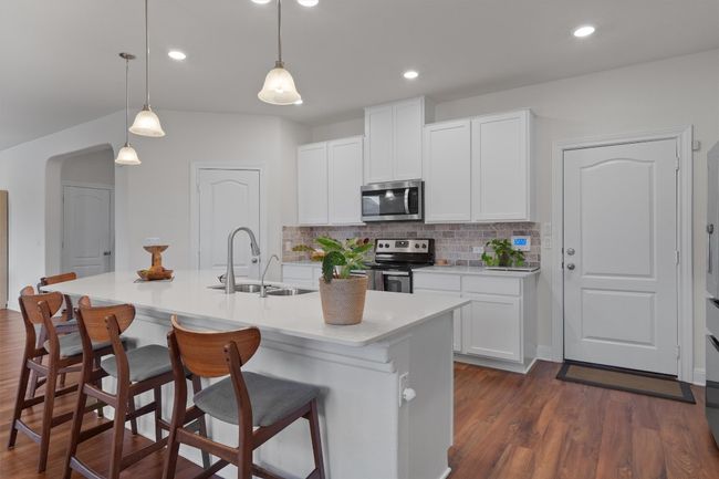 Kitchen with appliances with stainless steel finishes, decorative backsplash, a breakfast bar area, dark wood-style floors, and recessed lighting | Image 10