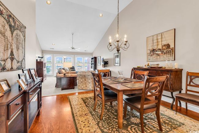 Dining area featuring high vaulted ceiling, recessed lighting, wood finished floors, and ceiling fan with notable chandelier | Image 6