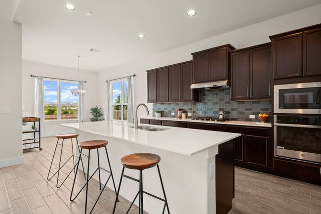 Kitchen with appliances with stainless steel finishes, recessed lighting, decorative backsplash, light countertops, and a kitchen bar | Image 18
