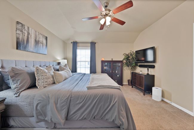 Bedroom with vaulted ceiling, light colored carpet, baseboards, and a ceiling fan | Image 31