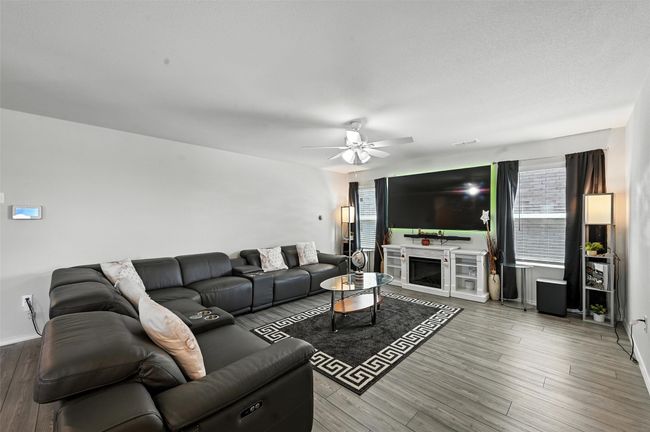 Living area featuring ceiling fan, wood finished floors, and a fireplace | Image 6