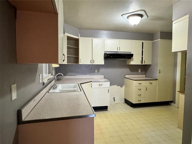 Kitchen featuring sink, white cabinetry, and light tile floors | Image 21
