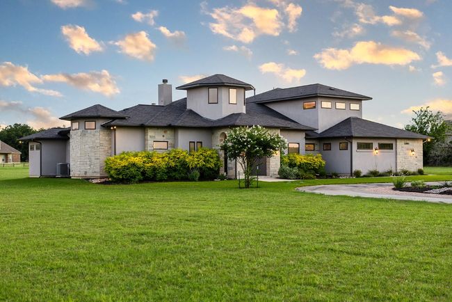 Prairie-style home featuring a chimney, stone siding, and a front yard | Image 4