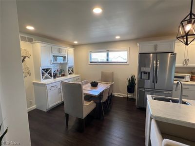 Kitchen featuring white cabinets, dark hardwood / wood-style flooring, and stainless steel fridge with ice dispenser | Image 2