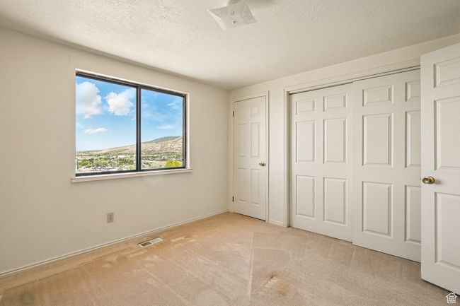 Unfurnished bedroom featuring light carpet, a textured ceiling, and a closet | Image 24