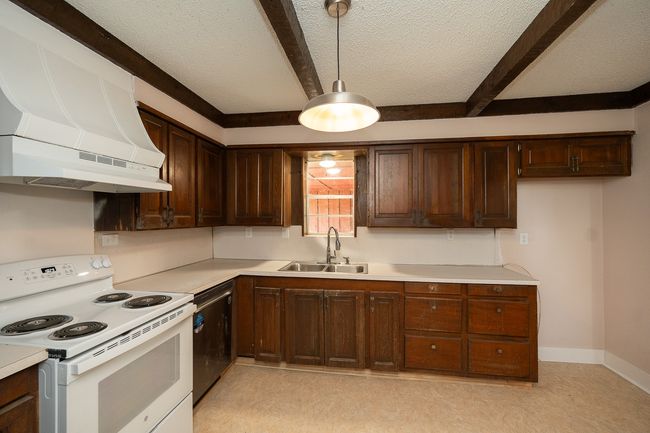 Kitchen featuring electric range, premium range hood, beam ceiling, light countertops, and a textured ceiling | Image 15