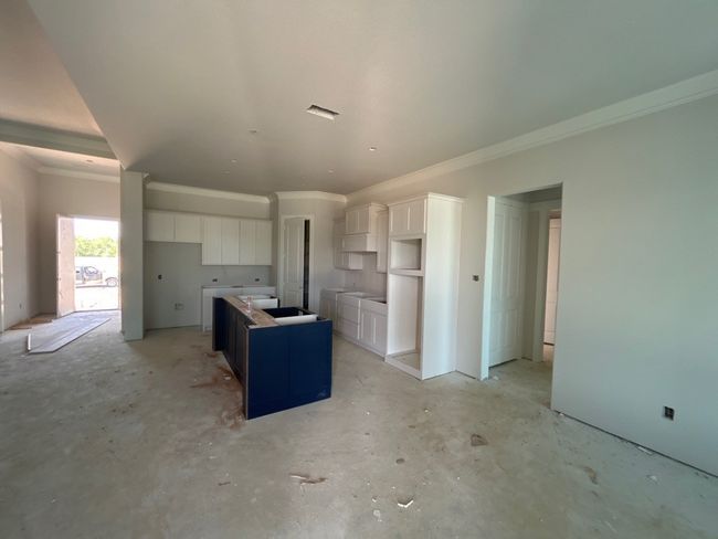 Kitchen featuring white cabinetry, crown molding, a kitchen island, and concrete floors | Image 5