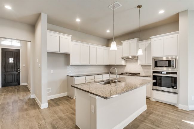 Kitchen featuring light stone counters, appliances with stainless steel finishes, sink, and white cabinets | Image 5