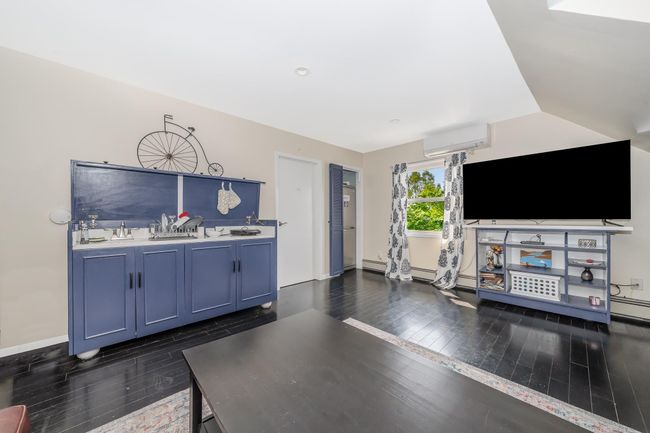 Unfurnished living room with dark wood finished floors, a wall mounted AC, a baseboard heating unit, baseboards, and vaulted ceiling | Image 21