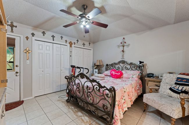 Bedroom featuring two closets, light tile patterned floors, a textured ceiling, and a ceiling fan | Image 10