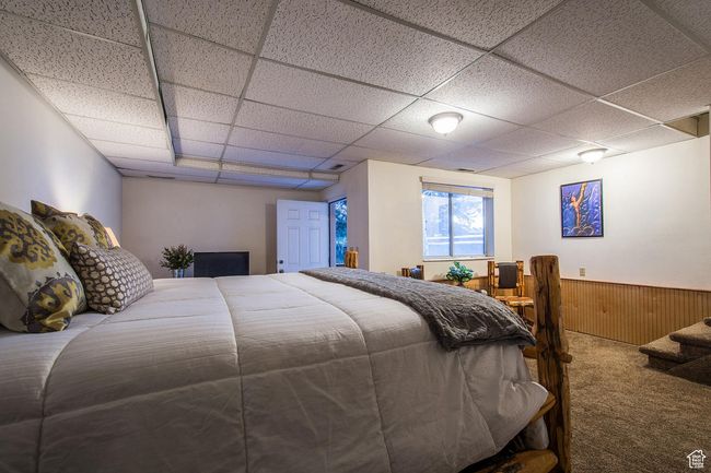 Carpeted bedroom featuring a drop ceiling and wooden walls | Image 7