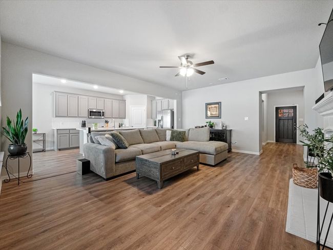 Living room with ceiling fan, baseboards, and light wood-type flooring | Image 11