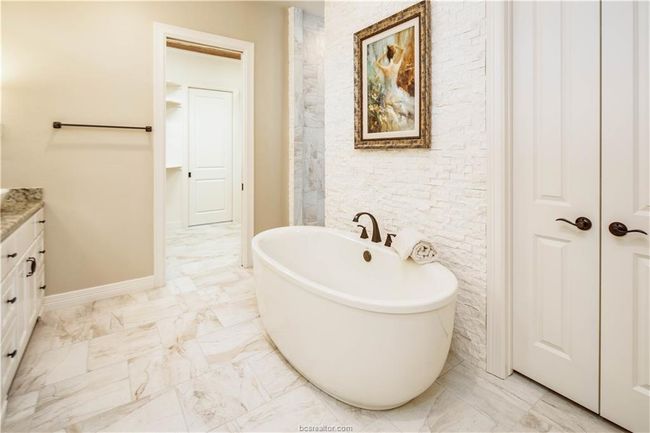 Bathroom featuring a freestanding bath, vanity, baseboards, and marble finish floor | Image 19