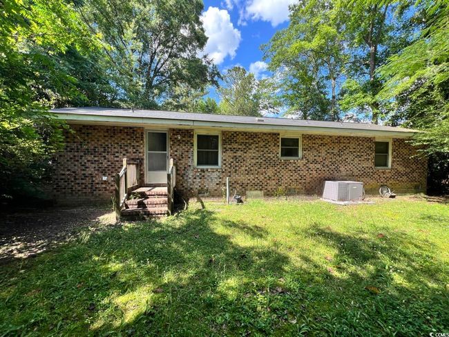 Back of property with central air condition unit, a yard, brick siding, and crawl space | Image 6