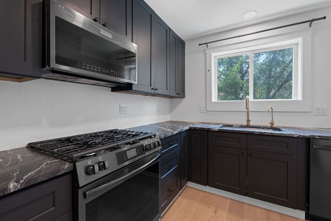 Kitchen featuring appliances with stainless steel finishes, dark stone counters, and light wood-style flooring | Image 9
