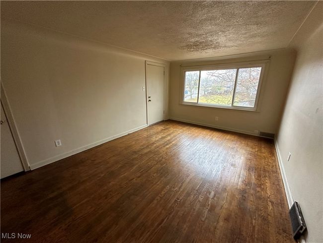 Spare room featuring a textured ceiling, visible vents, wood finished floors, and baseboards | Image 6
