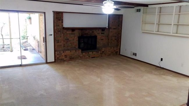 Unfurnished living room featuring a ceiling fan, carpet, baseboards, and a brick fireplace | Image 5