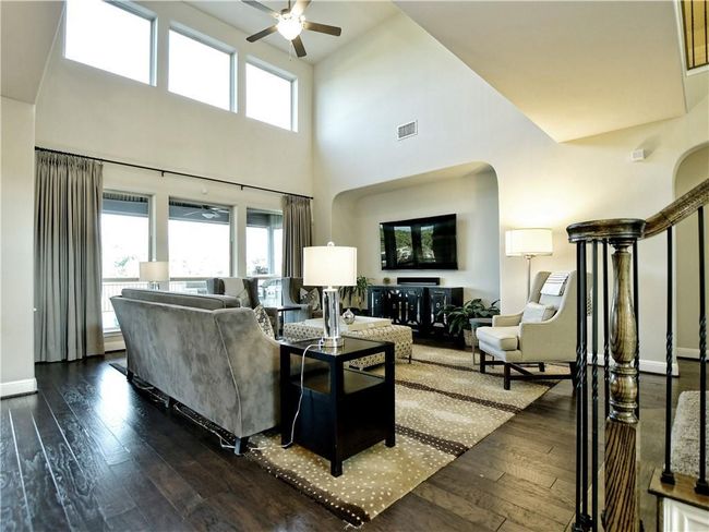 Living area with ceiling fan, dark wood-type flooring, a towering ceiling, and arched walkways | Image 11