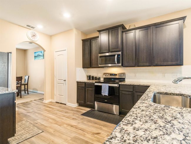 Kitchen with appliances with stainless steel finishes, sink, dark brown cabinets, and light hardwood / wood-style floors | Image 9