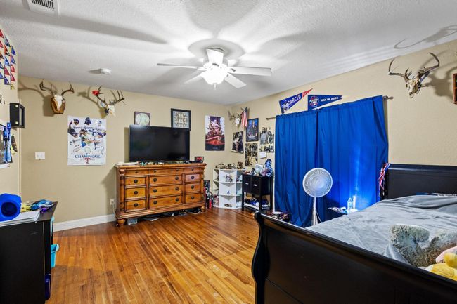 Bedroom featuring wood finished floors, visible vents, a ceiling fan, baseboards, and a textured ceiling | Image 32