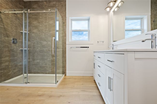 Full bath featuring double vanity, healthy amount of natural light, wood finished floors, and a shower stall | Image 22