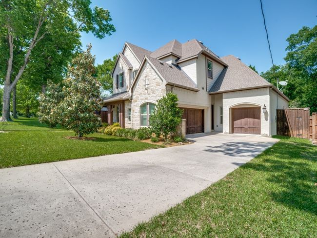 View of front of property with stone siding, concrete driveway, a garage, and a shingled roof | Image 22