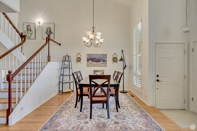 Dining space with stairs, light wood-style flooring, a towering ceiling, and a chandelier | Image 9